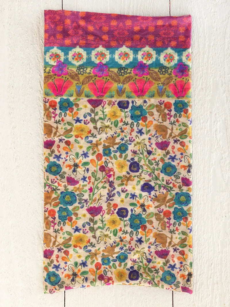 A vibrant boho bandeau headband with cream borders featuring multi-colored floral patterns and a bold pink top border