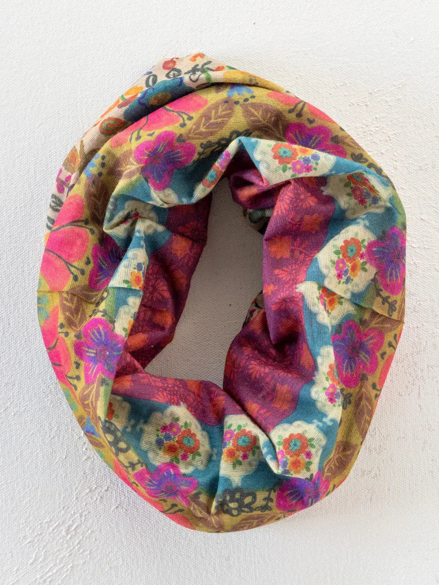 A vibrant multicolored floral boho bandeau headband with cream borders and soft fabric texture in bold pink blue purple yellow patterns