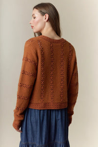 A warm terracotta knitted hole stripe bows front tie cardigan with intricate cable patterns and ribbed hem