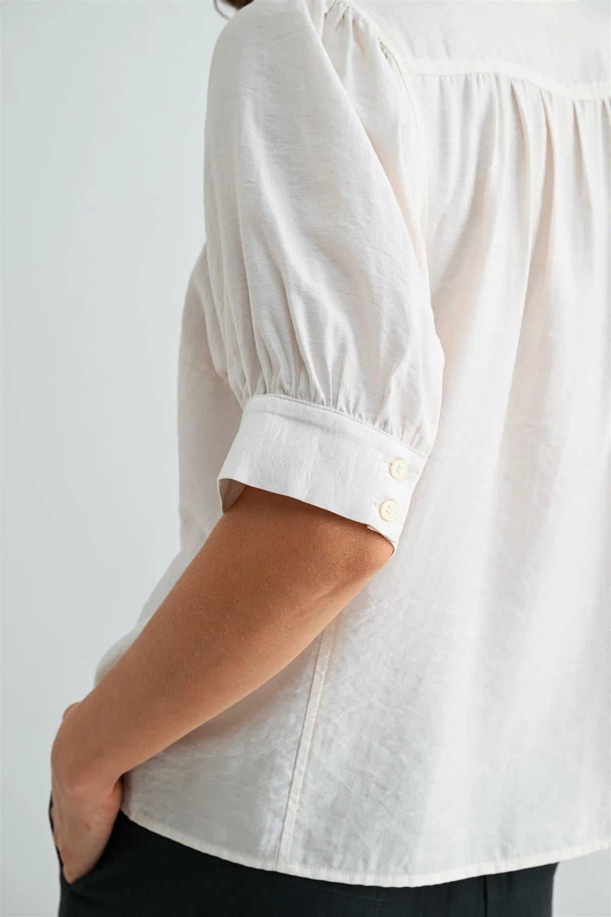 White short sleeve blouse with puffed sleeves and buttoned cuffs made from lightweight fabric for elegant wear
