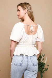 White blouse with short puff sleeves ruched waist and tied-back neckline showing the back side of the top