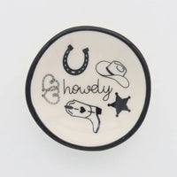 A white ceramic ring dish howdy with black rim featuring hand-drawn cowboy-themed illustrations for western decor