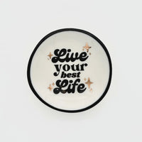 White ceramic ring dish with black rim featuring live your best life text and rose gold star accents for women’s boho chic clothing fans