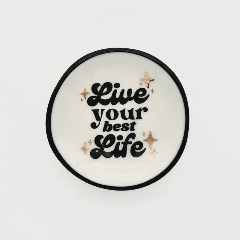 White ceramic ring dish with black rim featuring live your best life text and rose gold star accents for women’s boho chic clothing fans