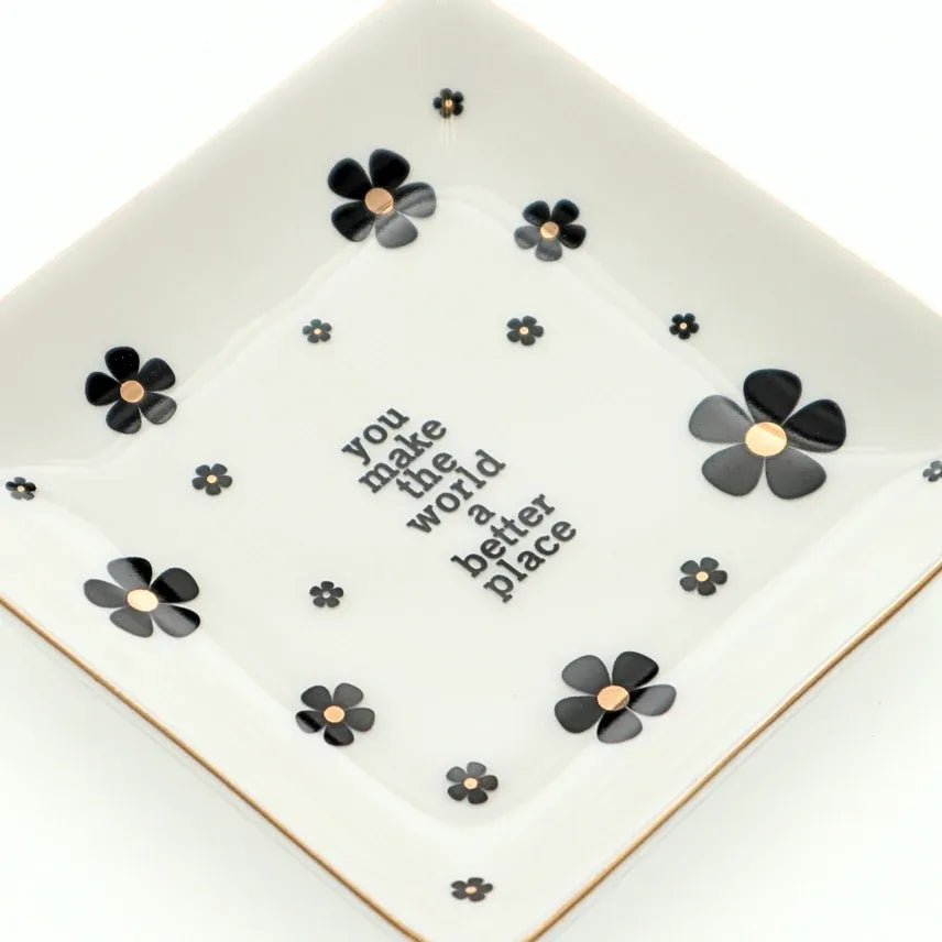 White ceramic trinket tray with black flowers and gold centers featuring you make the world a better place lettering