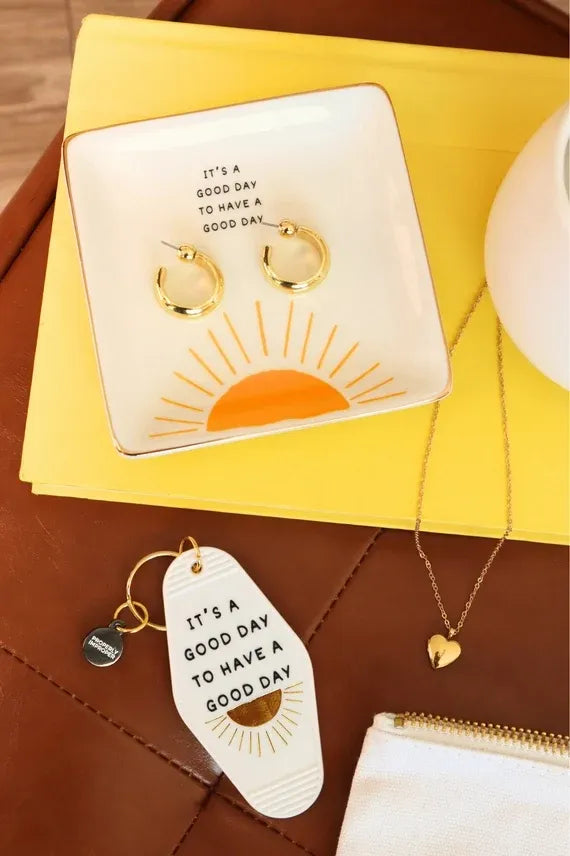 White ceramic trinket tray with gold rim sunburst design and phrase its a good day to have a good day printed in black