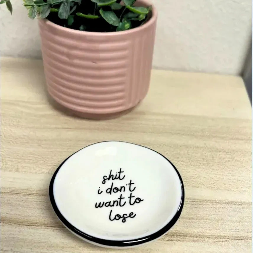White ceramic ring dish with black rim and handwritten text for storing rings from shop daisy women’s boho chic clothing collection