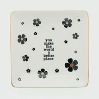 White ceramic trinket tray with black floral decals and gold rim featuring you make the world a better place text, shop daisy