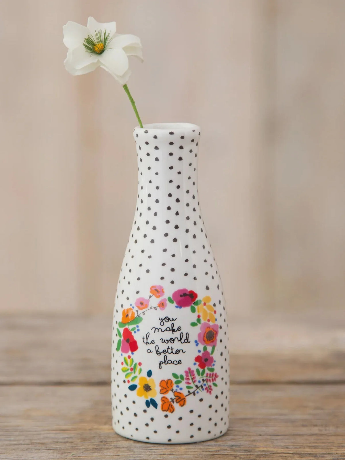 White ceramic bud vase with black polka dots and colorful floral wreath design featuring you make the world better phrase