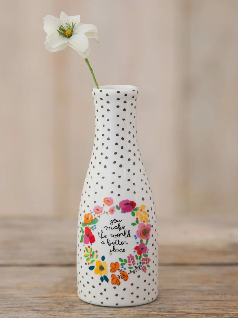 White ceramic bud vase with black polka dots and colorful floral wreath design featuring you make the world better phrase