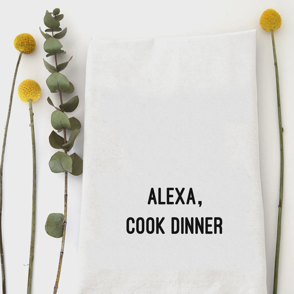 White cotton Alexa Cook Dinner tea towel with black text