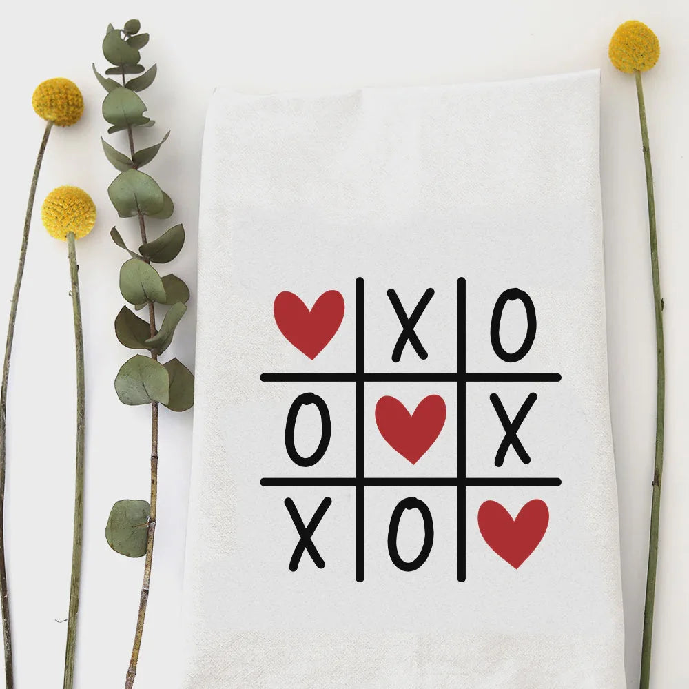 XOXO tea towel with white cotton tic-tac-toe design of red hearts and black Xs and Os