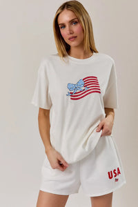 White cotton round neck t shirt with a glittery red and white usa flag graphic and blue bow design