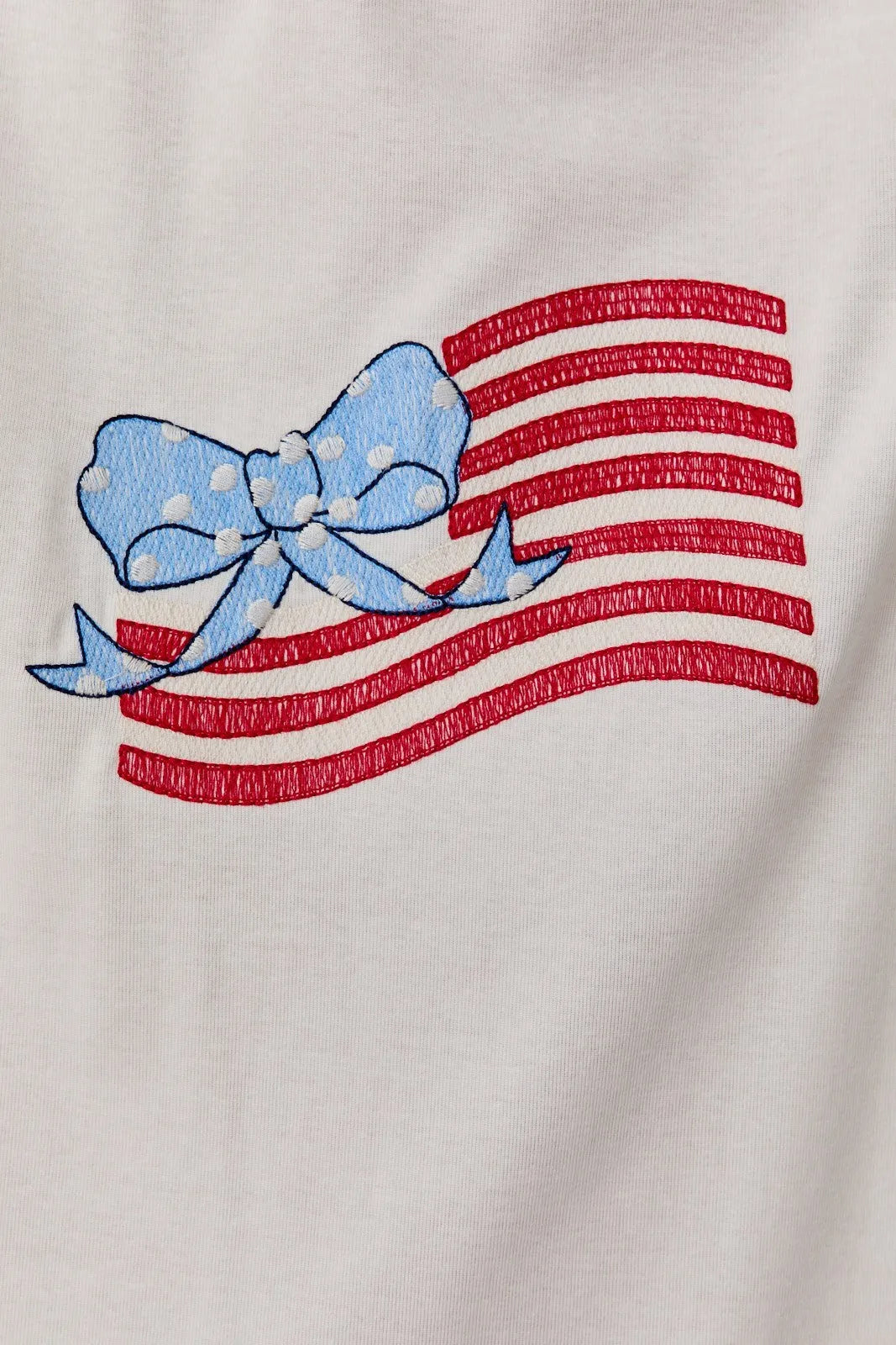 White cotton round neck t shirt with usa flag graphic featuring embroidered stripes and a light blue polka dotted bow