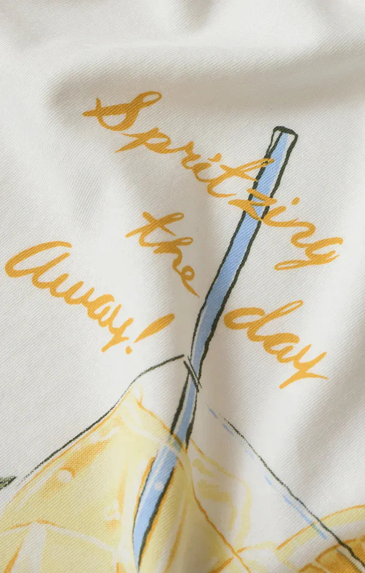 White cotton spritz boyfriend tee featuring a playful blue straw lemon graphic and gold cursive spritzing the day away text