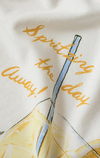 White cotton spritz boyfriend tee featuring a playful blue straw lemon graphic and gold cursive spritzing the day away text