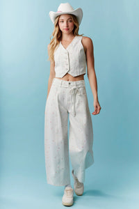White cowboy hat with subtle pink stitching paired with high waist mini bow print denim shorts with waist tie