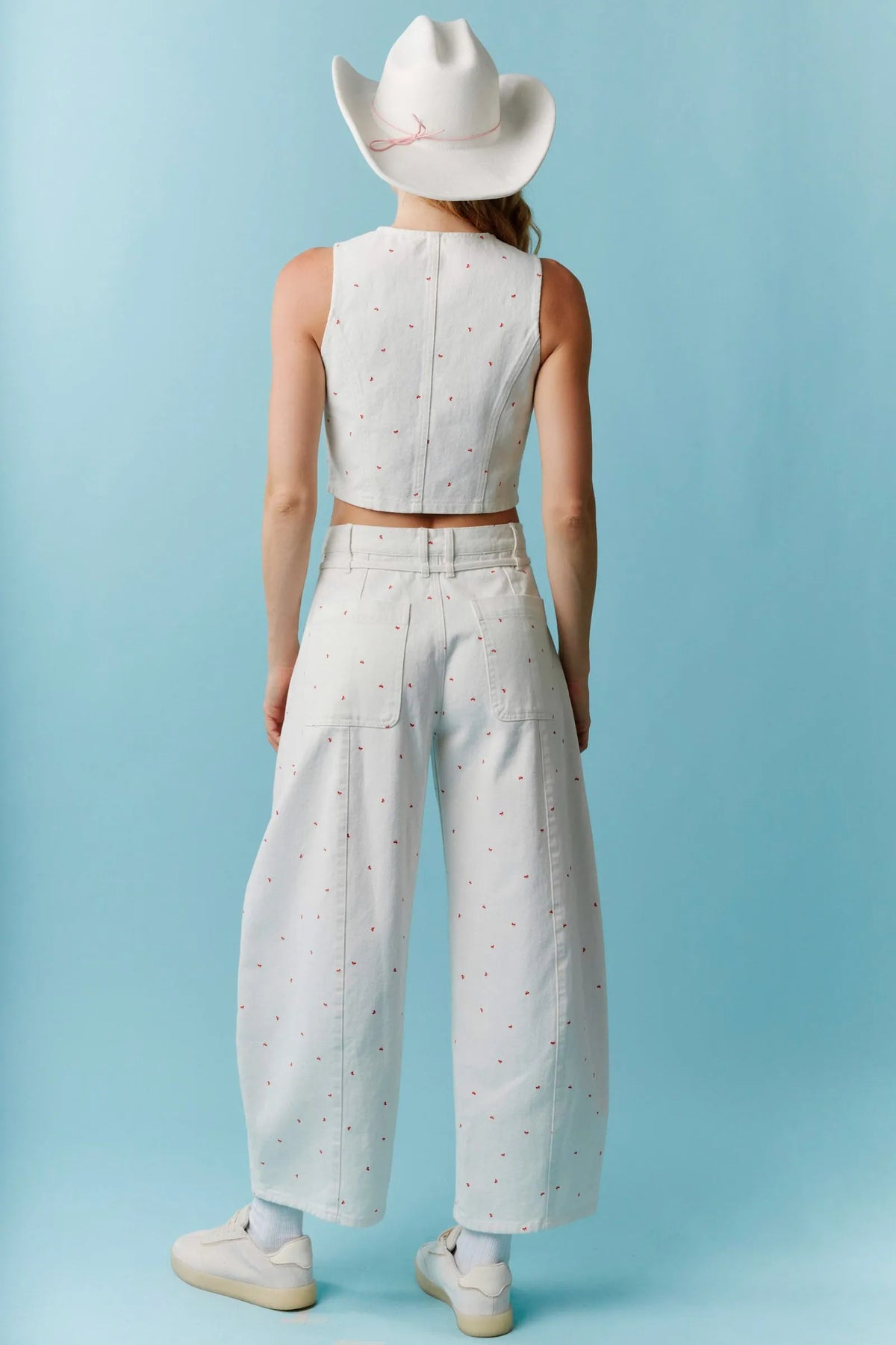 White cowboy hat with subtle pink stitched detail paired with high waist mini bow print waist tie barrel denim
