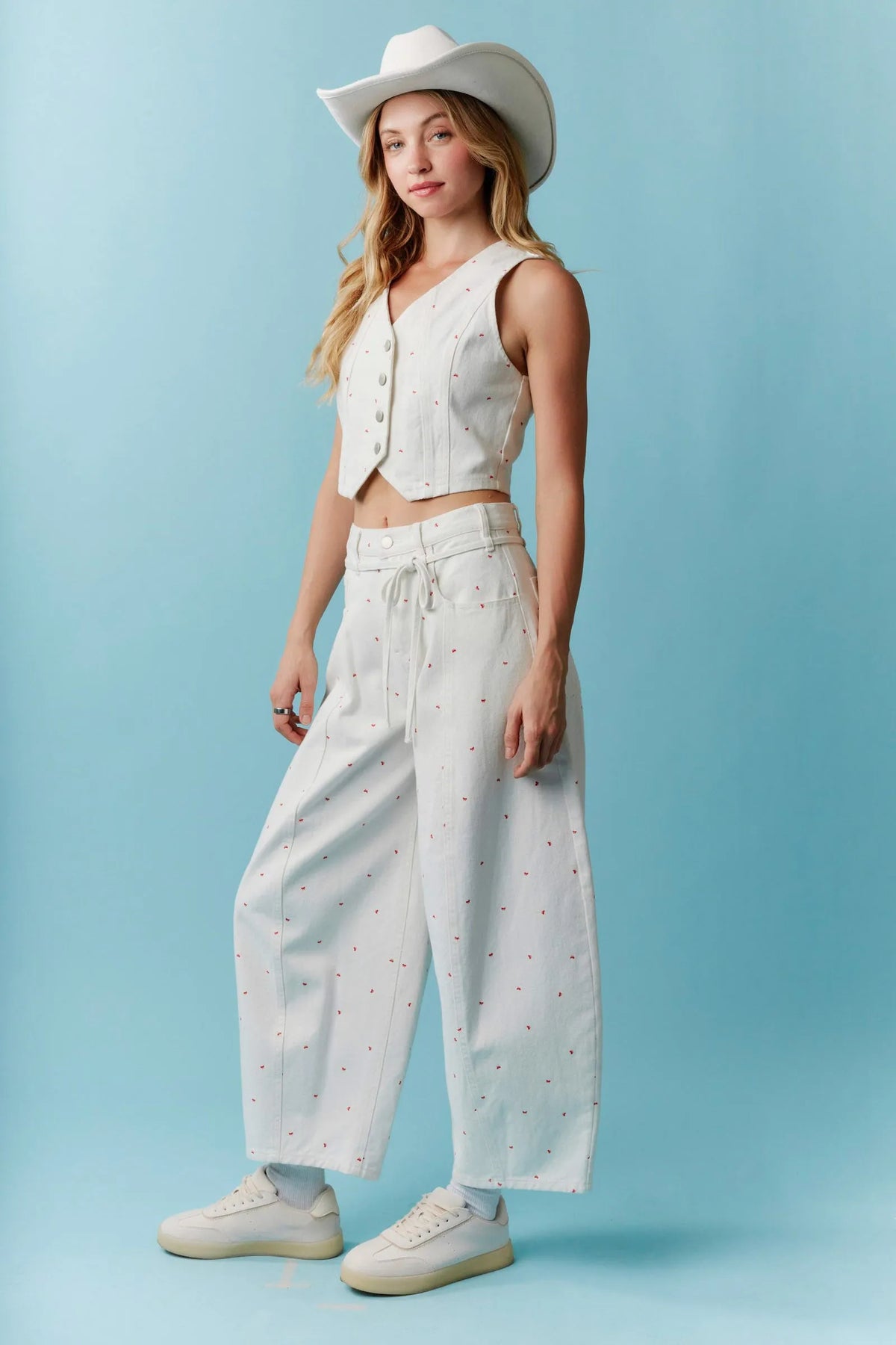 White cowboy hat with subtle dot pattern paired with high waist mini bow print waist tie barrel denim shorts