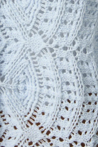 White crocheted lace fabric with intricate floral patterns on a long sleeve crochet light cardigan