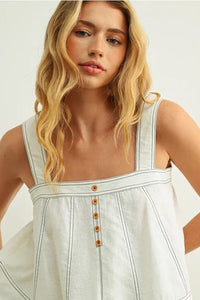 A white denim stitch detailed sleeveless top with thin straps square neckline and orange button accents down the front