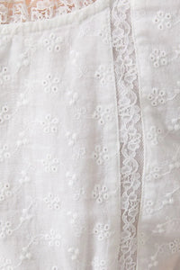 White cap sleeve scoop neck blouse with lace trim featuring delicate floral embroidered lace patterns and sheer lace trim