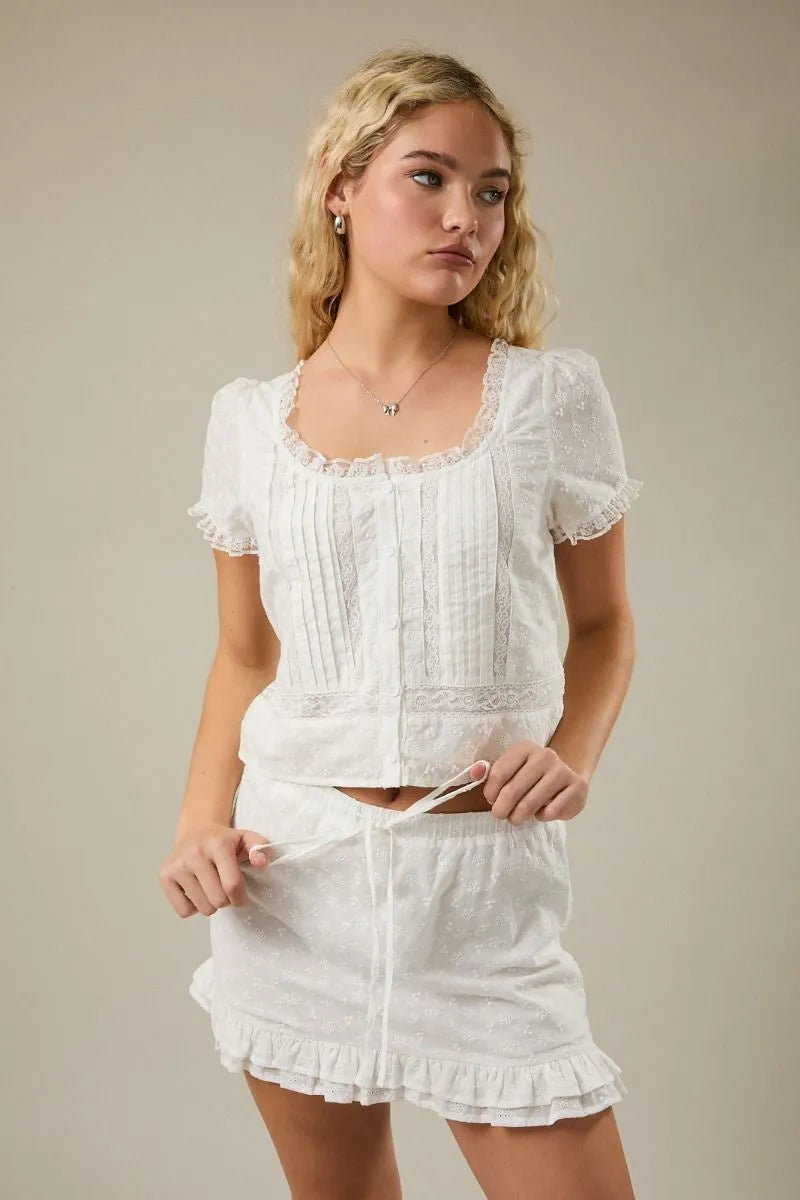 White embroidered lace trim crop top with cap sleeve scoop and puffed sleeves featuring vertical pleats
