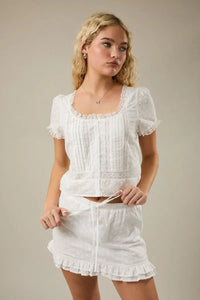 White embroidered lace trim crop top with cap sleeve scoop and puffed sleeves featuring vertical pleats