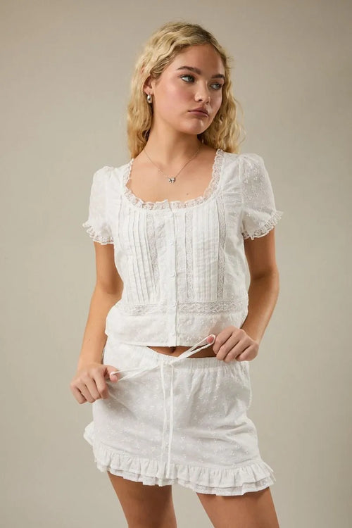 White embroidered lace trim crop top with cap sleeve scoop and puffed sleeves featuring vertical pleats