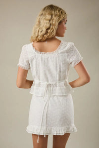 White embroidered short-sleeved dress with lace trim and tied waistband featuring a cap sleeve scoop neck design