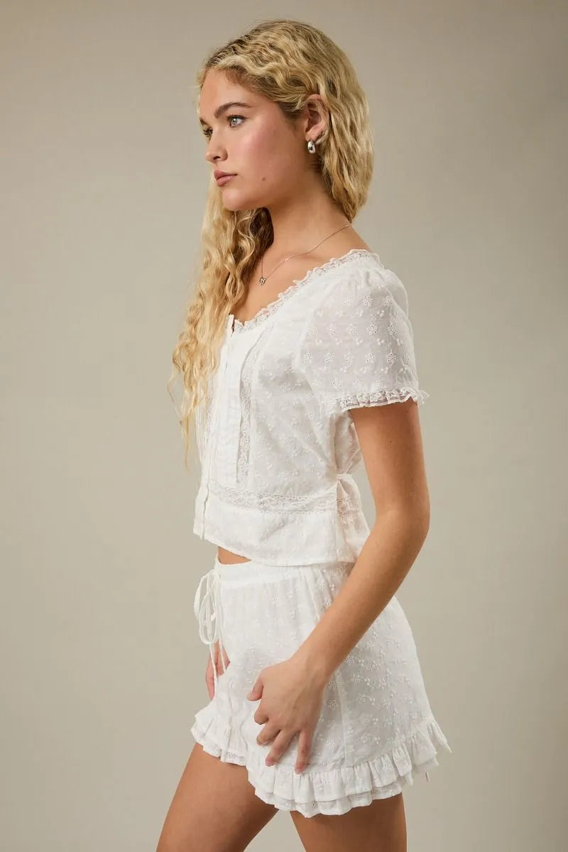 White eyelet crochet cap sleeve scoop neck blouse with lace trim and ruffled hem in short sleeves design