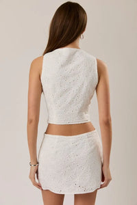 White eyelet crochet sleeveless high neck bow detail top paired with matching mini skirt set for summer wear