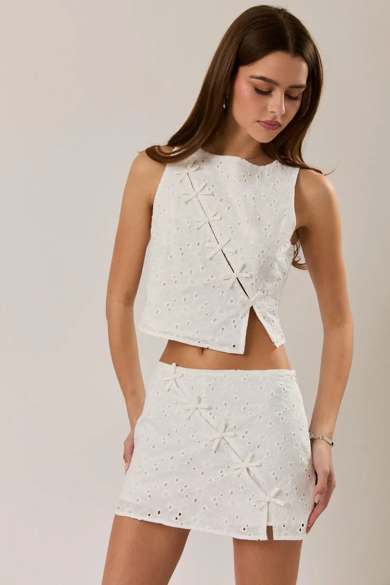 White eyelet sleeveless high neck crop top with bow detail paired with mini skirt featuring star appliqués