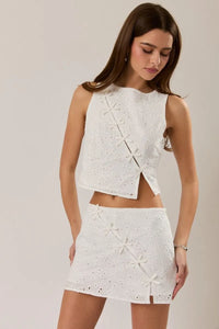 White eyelet sleeveless high neck crop top with bow detail paired with mini skirt featuring star appliqués