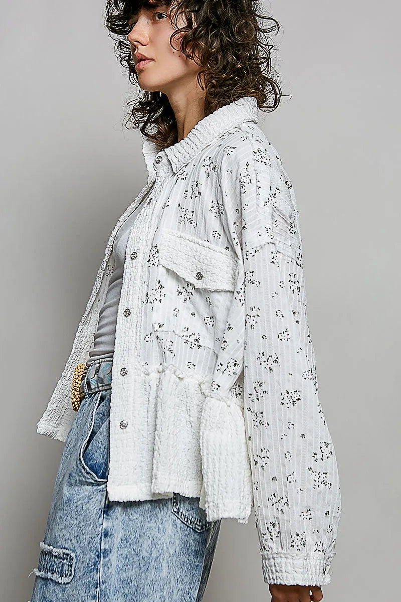 White floral shacket with floral ruffle detailing, textured ribbed fabric, and button closures on front pockets
