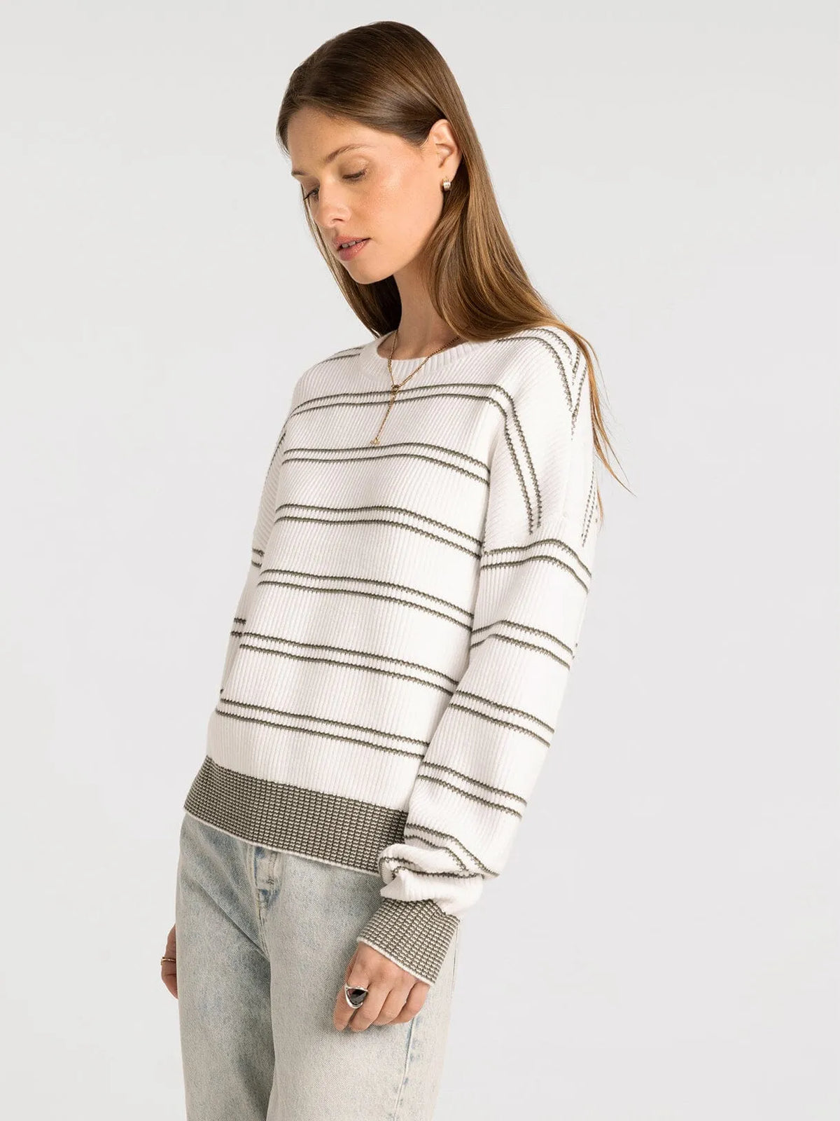 A white and gray striped knit sweater with ribbed crew neck cuffs and hem featuring a textured pattern supply ely sweater