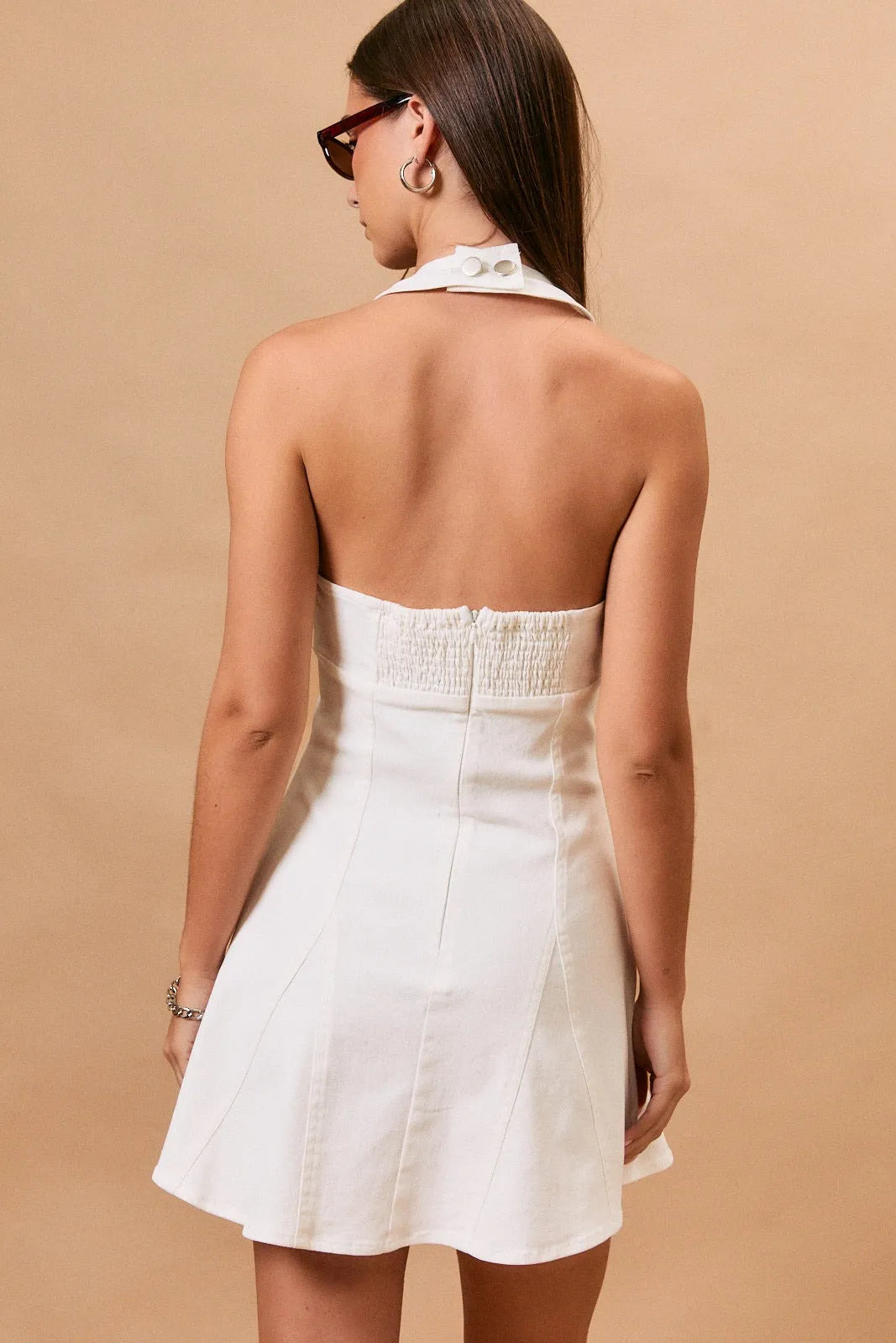 White halterneck mini dress with smocked waistband and neck seam denim detailing in structured silhouette