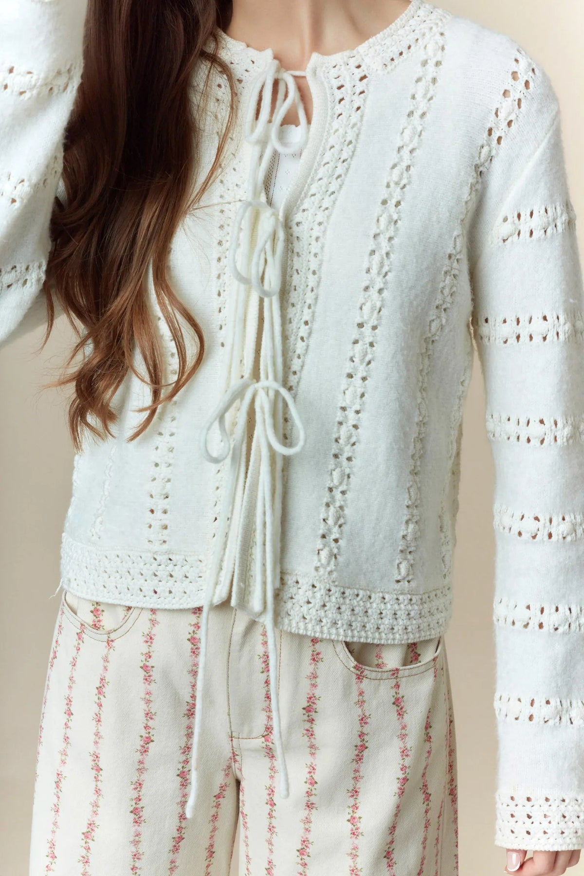 White knit cardigan with intricate hole stripe bows lace detailing and a front tie closure in a stripe bows design