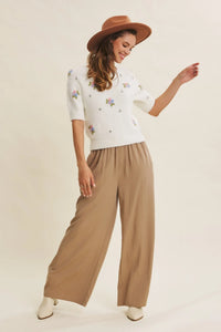 White knit sweater with delicate pastel floral embroidery paired with wide leg step washed pants