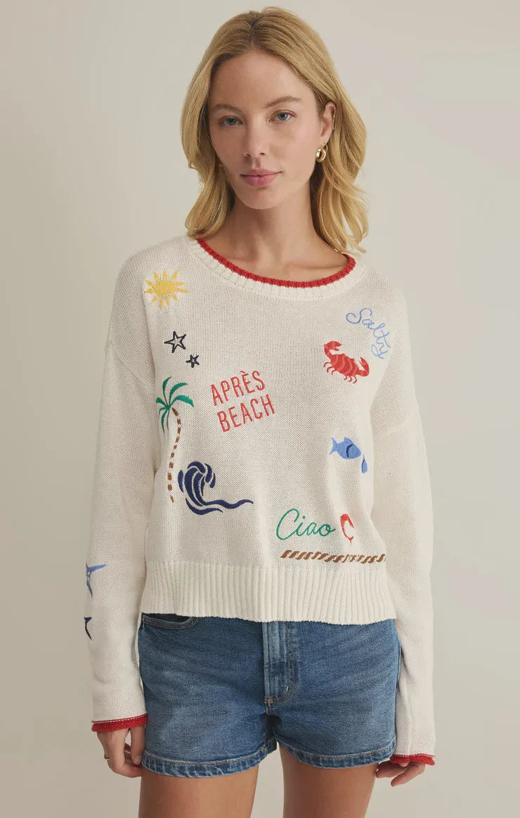 White knit day sienna sweater with colorful embroidered beach-themed graphics and red trim on neckline and cuffs