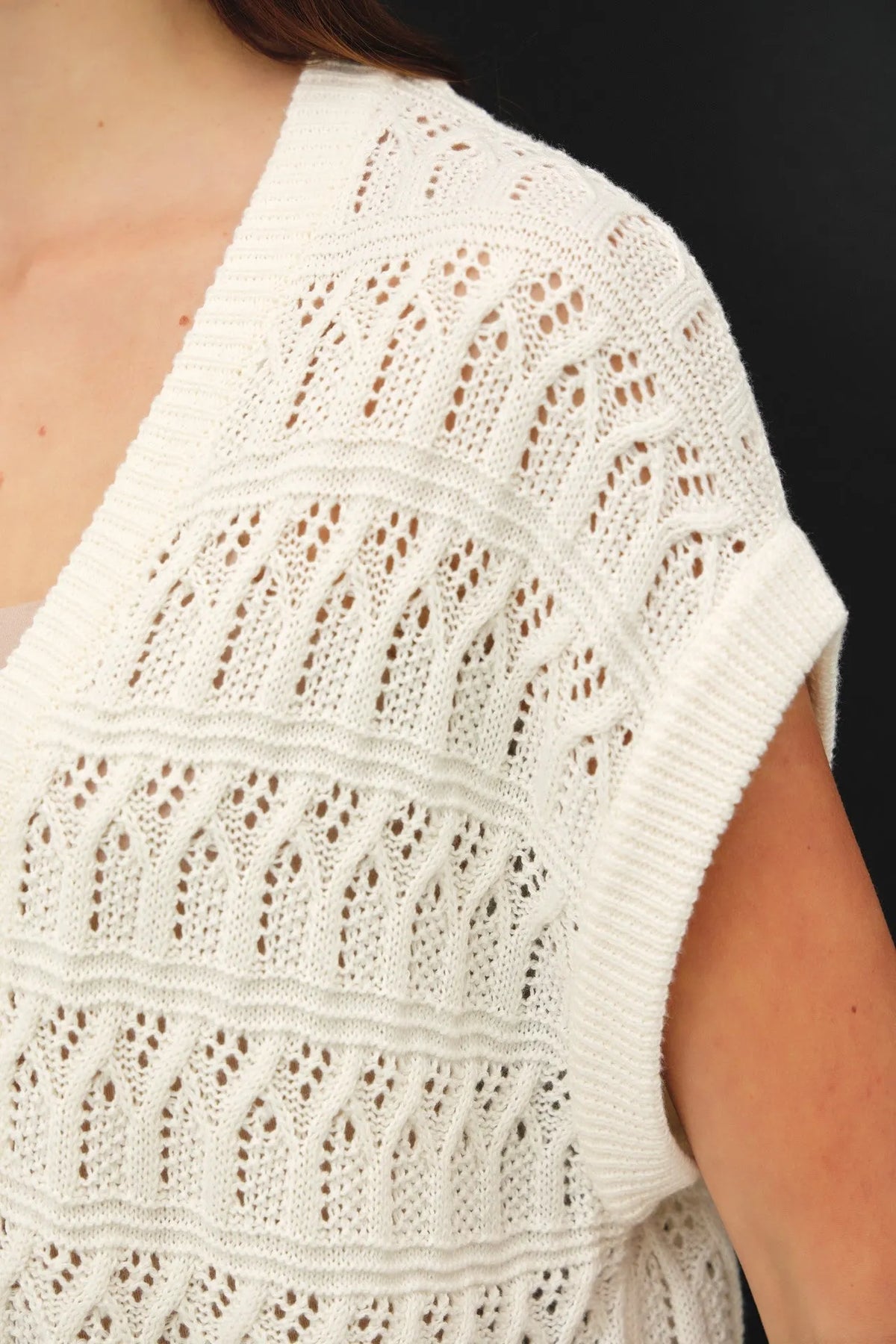 White crocheted knit boxy sleeveless top with intricate lace-like patterns and ribbed edges for a knit boxy open look