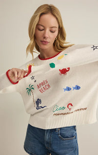 A white knitted sienna sweater with colorful embroidered beach motifs and red trim from the day sienna collection