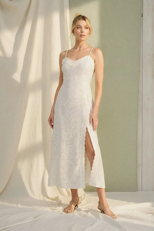 White lace maxi dress with delicate spaghetti straps, high slit, scalloped lace trim, and polka dot accents