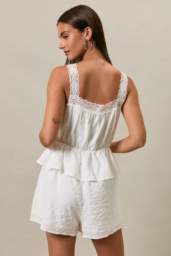 White lace-trimmed peplum romper with square neck lace trim detail and ruffled tiers in a relaxed fit