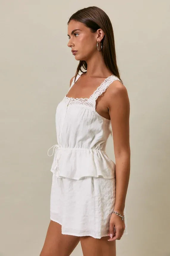 White lace-trimmed sleeveless romper with tiered peplum waist and drawstring detail