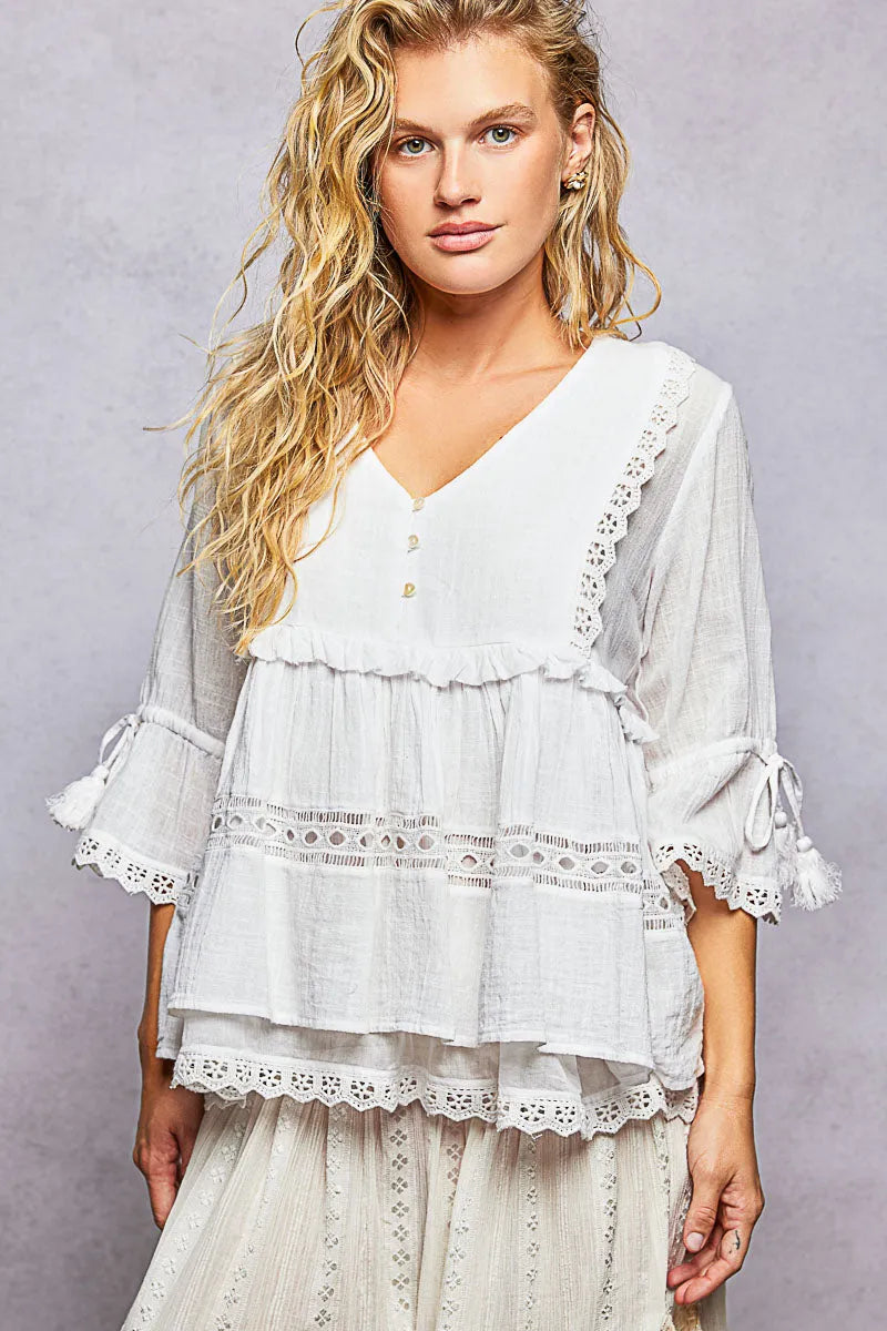 A white boho v neck half sleeve relaxed fit blouse with layered lace trim and ruffled sleeves