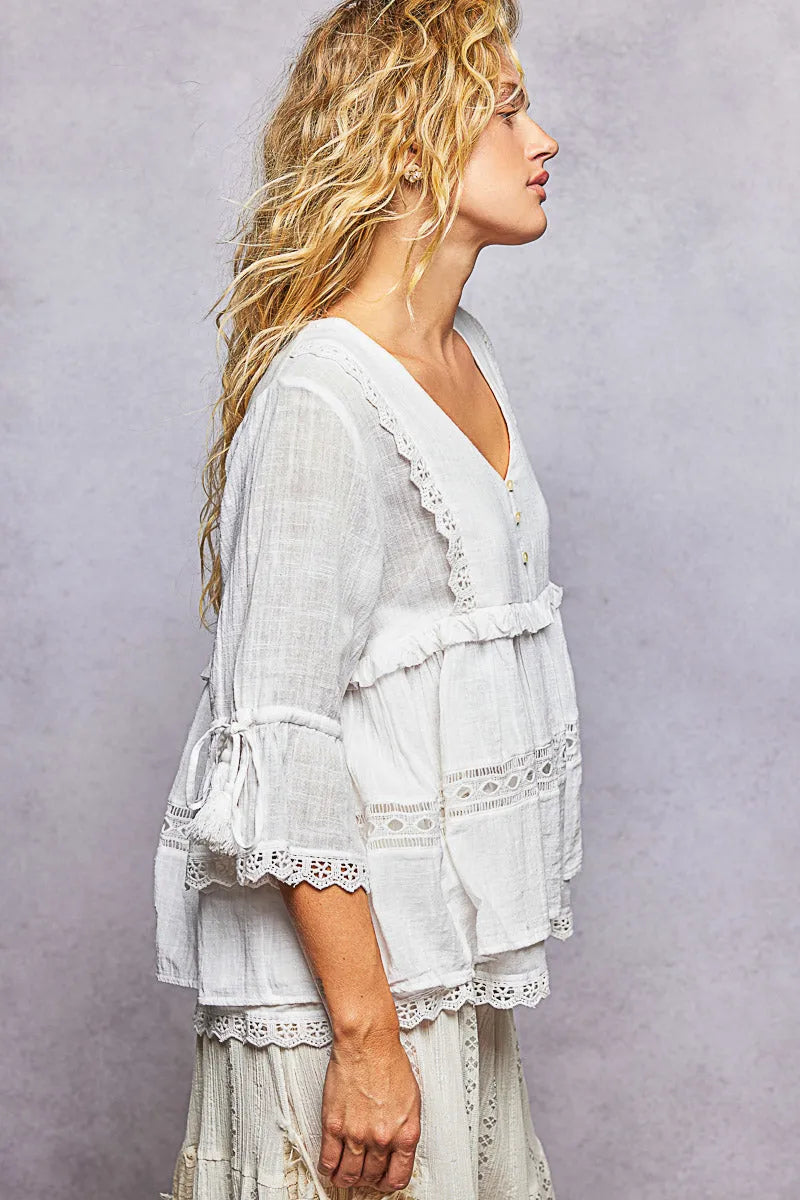 A white lightweight boho v neck half sleeve blouse with delicate lace trim and relaxed fit ruffled sleeves