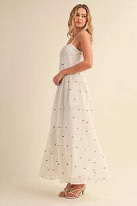 A flowing white maxi dress with delicate black polka dot pin tuck detailing and thin spaghetti straps