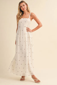 A flowing white maxi dress with delicate black polka dot print and pin tuck detailing with thin spaghetti straps