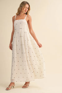 A flowing white maxi dress with delicate black polka dot print and pin tuck detailing with thin spaghetti straps
